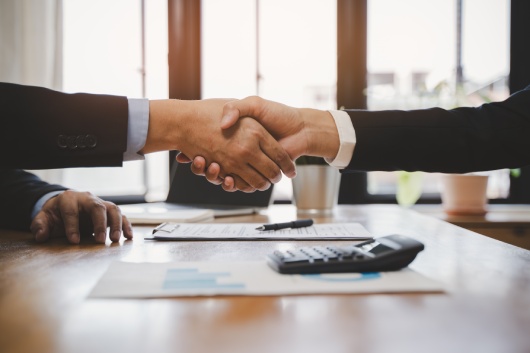 Top view hands of agent and client shaking hands after signed contract buy new apartment.