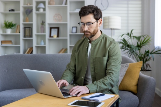 Focused man working on laptop in stylish home office setting. Productivity, remote work, freelance, and technology concepts.