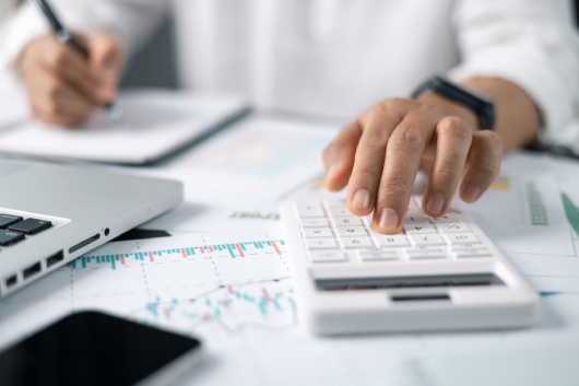 Business financing accounting banking concept. Businesswoman hand doing finances and calculate on desk about cost at home office. Woman working on desk with using calculator, finance accounting.