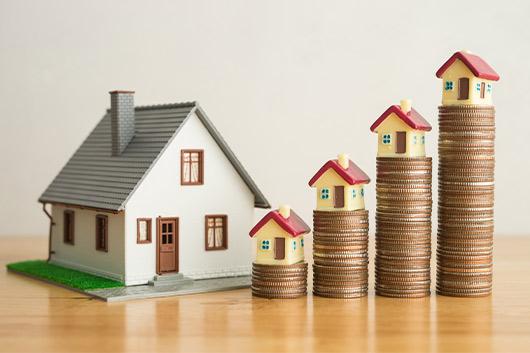 cozy house next to a stack of coins on a table, symbolizing financial planning for your dream home in Texas.