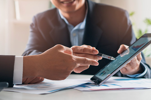 Two business professionals review information on a tablet, discussing mortgage options for finding a dream home in Texas