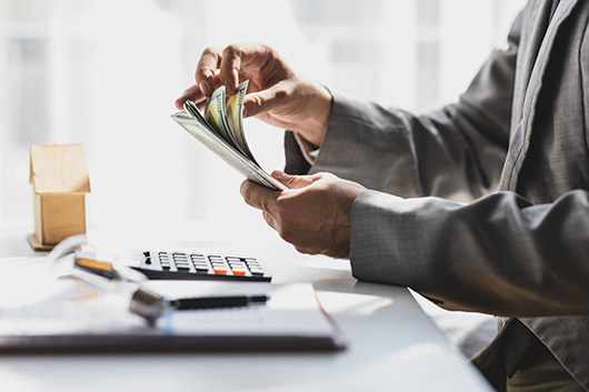 A man in a suit counts money, illustrating business checking features and financial management.